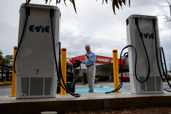 Evie Networks Chris Mills with an electric vehicle at the charging station at Hungry Jacks Cabramatta charging site.