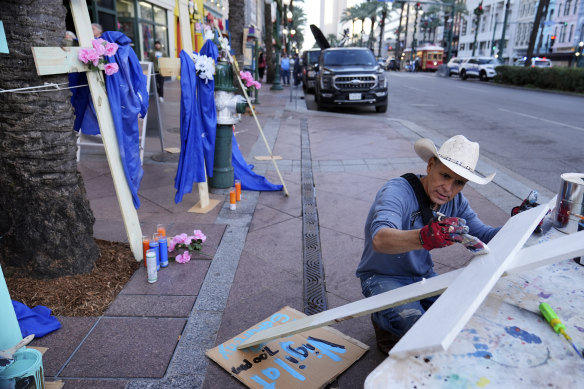 Artist Roberto Marquez, of Dallas, sets up a memorial of crosses along Canal Street.