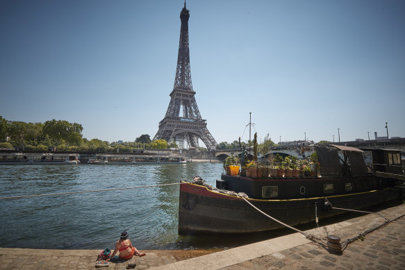 Bir Parisli, Paris'te sıcaklıklar 34°C'ye ulaşırken ve Fransa'nın büyük bir bölümünde sıcak hava dalgası yaşanırken, karantinanın gevşetilmesinden bu yana bugün ilk kez yeniden açılan Eyfel Kulesi'ne bakan Seine nehrinin kıyısında dinleniyor.