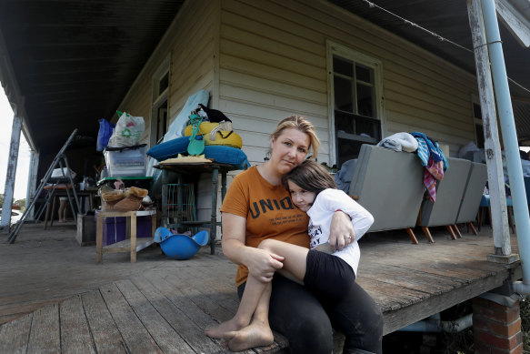 Em Trotter and daughter Evie-Meg, 6, sit on the verandah of their flood-affected home in Croki, near Taree.