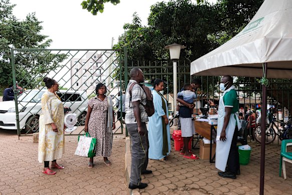 Le persone si mettono in fila per farsi controllare la temperatura fuori da un ospedale di Kampala.