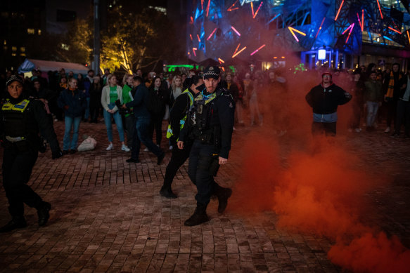 Police get rid of the single flare lit at Fed Square on Thursday night.