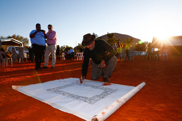 Noel Pearson signs the canvas for the Uluru Statement from the Heart. 