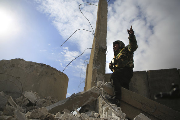 A Kurdish-led Syrian Democratic Forces fighter, stands at a damaged part of the defence wall of Gweiran Prison in Hassakeh, northeast Syria. 