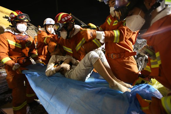 Rescuers place a boy pulled from the rubble of a collapsed hotel on a stretcher in Quanzhou, south-east China.