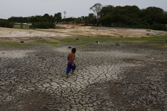 A boy walks across a dry, cracked area of the Negro River near his houseboat in Manaus. The river reached its lowest level in more than 120 years on Monday.