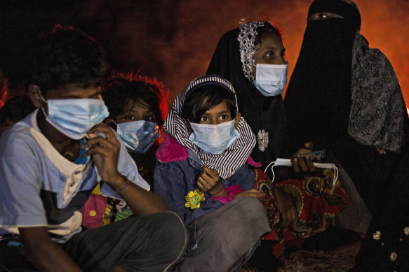 Rohingya women and children sit by a fire on the beach of Idaman Island, off the coast of Aceh. 