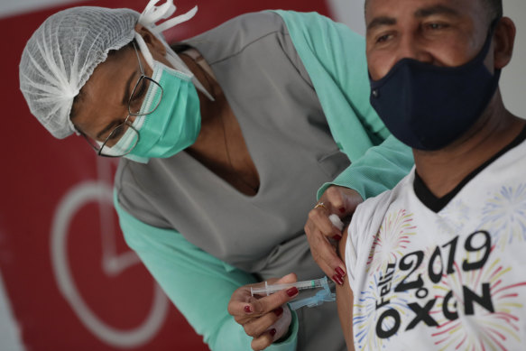 A health worker gives a shot of the Johnson & Johnson COVID-19 vaccine to a man at a homeless shelter in Brasilia, Brazil.