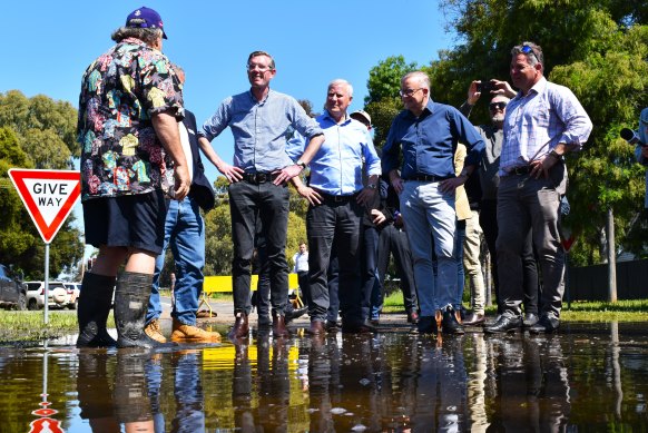 NSW Premier Dominic Perrottet (left) and Prime Minister Anthony Albanese chatting to a local in the town of Forbes last week after it was flooded. 