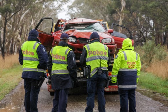 Police officers with the wrecked car the day after the crash.