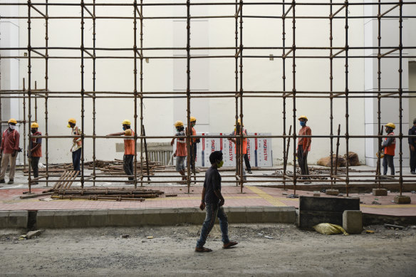 Indian laborers wearing masks report for the day's work at a metro rail construction site in Kochi, Kerala.