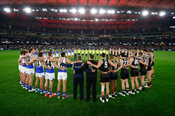 North Melbourne and St Kilda players, coaches and umpires form a circle as a show of support against gender based violence.