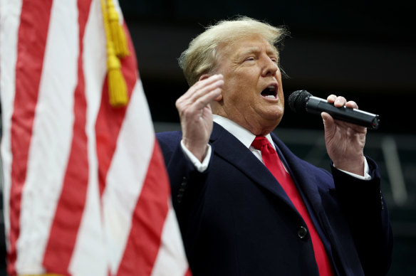 Former president Donald Trump speaks to voters during a visit to a caucus site in Clive, Iowa.