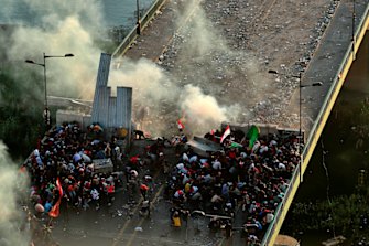 Anti-government protesters take cover while Iraq security forces fire tear gas during a demonstration in Baghdad, Iraq on Saturday.