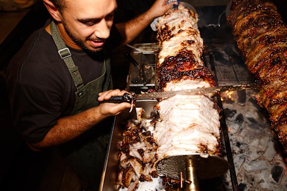 Alexis Agathocleous carving meats on the charcoal grill. 