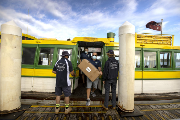 Cronulla High principal Tony Ibrahim and deputy principal Joel Burnett disembark at Bundeena
 with 460 rapid antigen test kits for students.