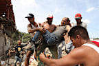 Neighbours carry a man rescued from the rubble of a collapsed building after earthquakes struck La Guaira, Venezuela,
