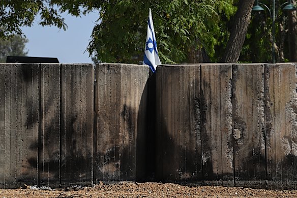 An Israeli flag flying above damaged blast walls in Kibbutz Be’eri.