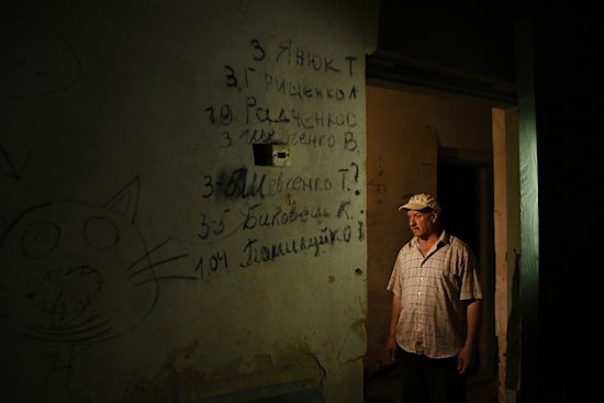 Ivan, 62, stands in the doorway of a basement room in a school in Yahidne where nearly the entire village of 371 people were held. The seven names on the wall are of those who died.
