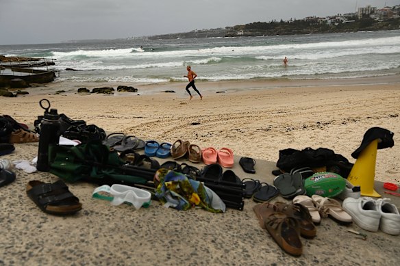 At man runs along Bondi Beach near the abandoned possessions belonging to people who fled Bondi Beach last night.