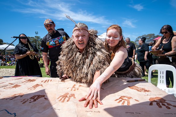 Dja Dja Wurung man Rodney Carter puts his handprint on a kangaroo skin with the help of a family member during a celebration of Victoria’s treaty with Indigenous peoples.