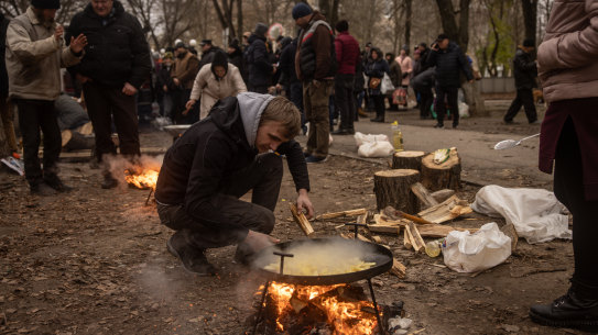 A volunteer puts wood on a fire to cook hot meals for residents in Kherson city centre on December 1.