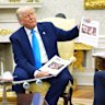 President Donald Trump shows documents as he meets South Africa’s President Cyril Ramaphosa in the Oval Office of the White House, Wednesday, May 21, 2025, in Washington. (AP Photo/Evan Vucci)