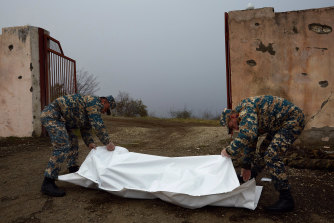 Armenian servicemen collect the bodies of soldiers killed fighting for Azerbaijan on the road where the final days of battle unfolded between the two armies.