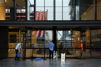 Workers clean the entrance to an office building in Parramatta as people start returning to work in offices.