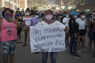 A woman holds a sign that reads "There are dead and sick. They deserve to live. They are human beings," as relatives of the inmates gather outside Castro Castro prison in Lima.