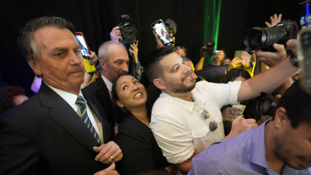 Brazil’s right wing former President Jair Bolsonaro, left, is surrounded by supporters as he leaves after speaking at an event hosted by conservative group Turning Point USA, at Trump National Doral Miami.
