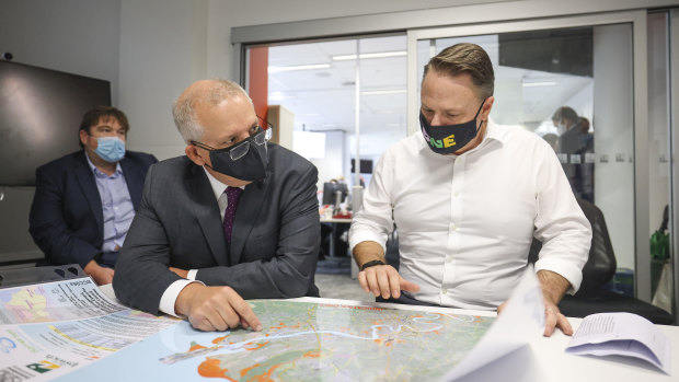 Prime Minister Scott Morrison and Brisbane lord mayor Adrian Schrinner check a map of flooded regions.