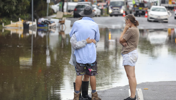 People hug while watching the floodwaters at Eagle Tce, Auchenflower in Brisbane.