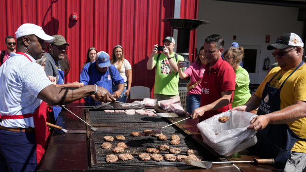 Republican presidential candidate Senator Tim Scott works the grill at the Iowa Pork Producers Tent.