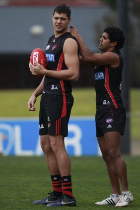 Essendon footballer Alwyn Davey (right) helps teammate Paddy Ryder in 2012.