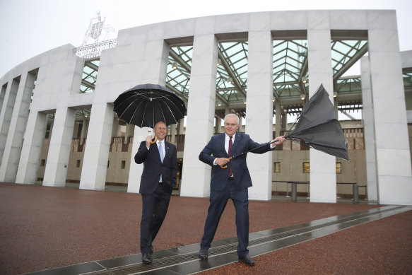 Treasurer Josh Frydenberg and Prime Minister Scott Morrison arrive for post-budget day interviews on a windy, rainy morning. 