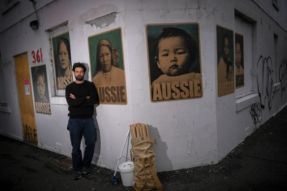 Peter Drew in front of his posters featuring women and children who were born in Australia but had to get exemptions to travel because of the White Australia Policy.