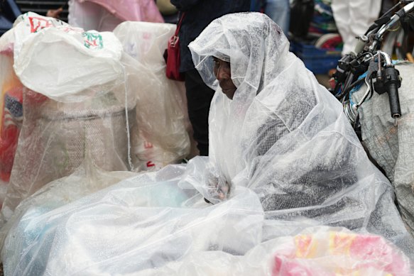 A street vendor covers up in plastic during light rain in the Petion-Ville neighbourhood of Port-au-Prince, Haiti, on Tuesday (local time).