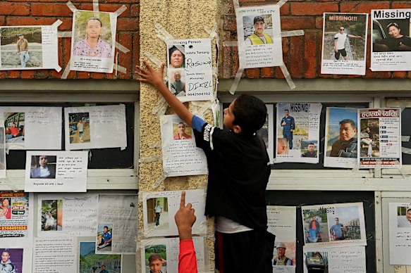 Bibek Pariyar, 12, helps people put up posters of their loved ones.