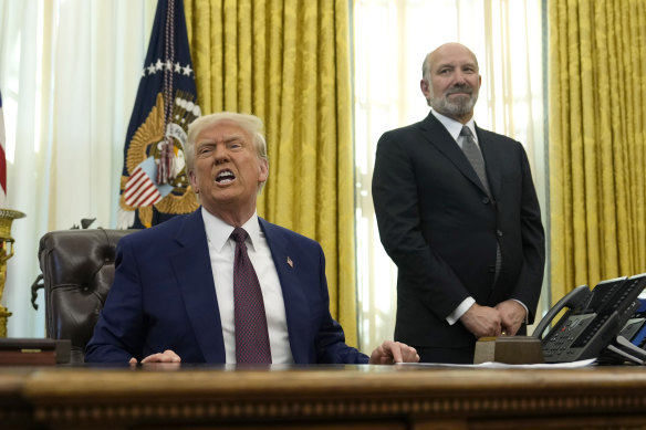 President Donald Trump speaks to reporters in the Oval Office on Thursday as Commerce Secretary nominee Howard Lutnick watches on.