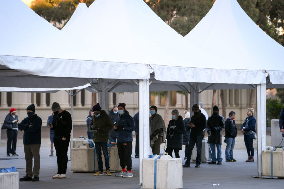 People queue to receive the COVID-19 vaccine at the vaccination hub at the Royal Exhibition Building in Carlton.