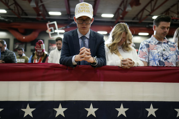 Supporters bow their heads in prayer before Donald Trump’s “commit to caucus” rally in Clinton, Iowa.