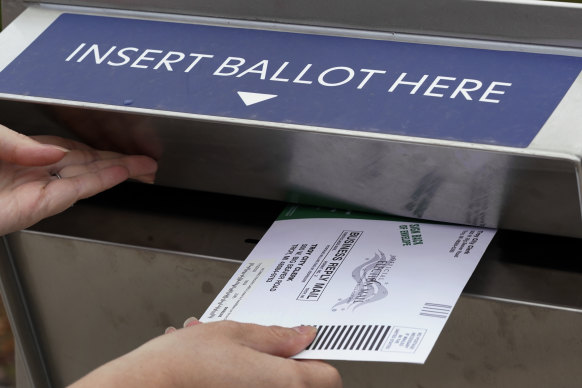 A Michigan voter inserts her absentee ballot into a drop box.