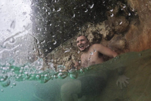 A young man cools off under a waterfall at the aquifer-fed Venetian Pool in Coral Gables, Florida, on Thursday.