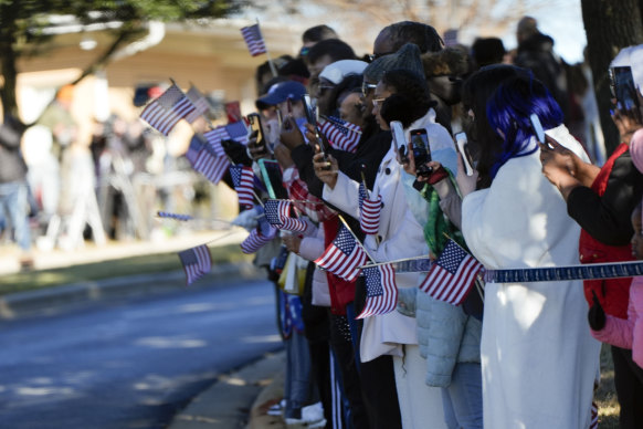 People watch the hearse carrying the flag-draped coffin of  Jimmy Carter.
