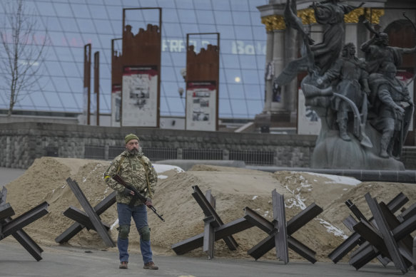 An armed man stands near a barricade during an air raid alarm in Maidan Square, in Kyiv.
