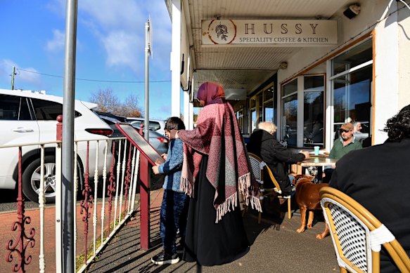 A woman wearing a hijab walks along the streets of Young with her son.