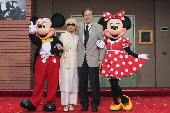 Elizabeth Gluck and Richard M. Sherman with Mickey and Minnie Mouse at the ceremony honouring the Sherman Brothers with the renaming of Disney Studios Soundstage A  in 2018.