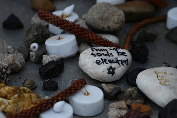 A matzeivah with the words “May your souls be elevated” is placed among candles and flowers at a memorial for the Bondi terror attack victims. 
