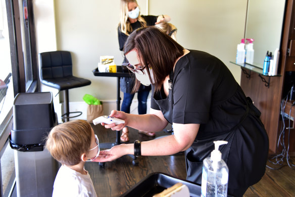 Cooper Gonzalez, 4, gets his temperature checked before a haircut in Albany.